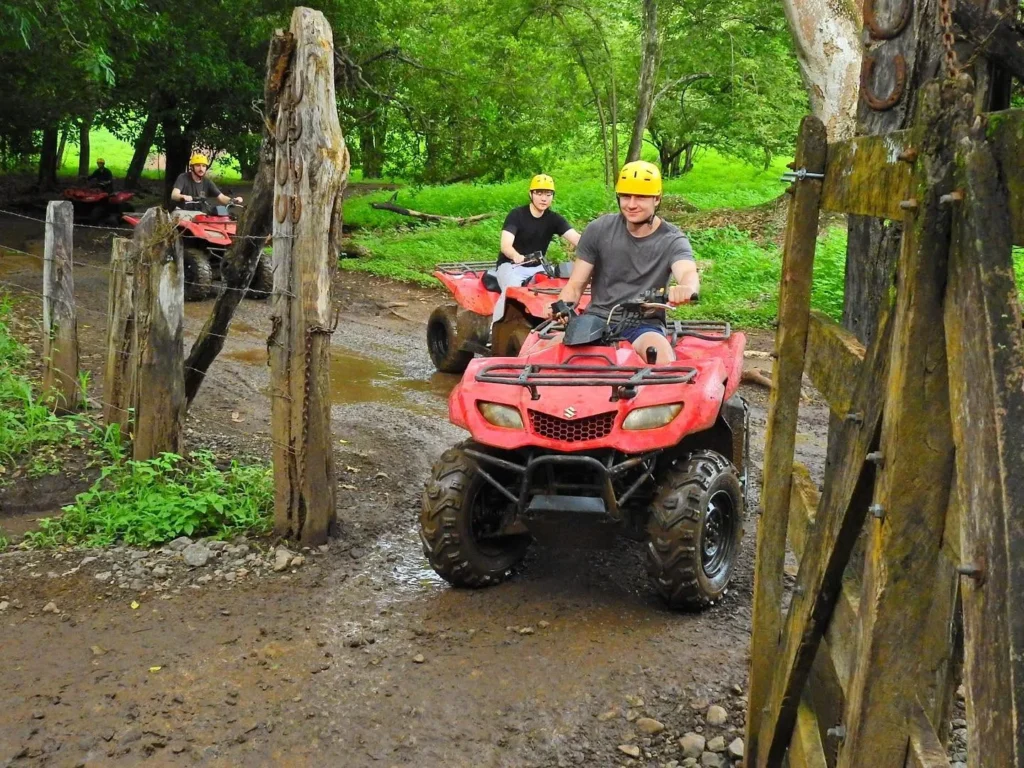 Riders on ATVs passing a wooden farm gate on the private property at Congo Trail, Sardinal, Guanacaste
