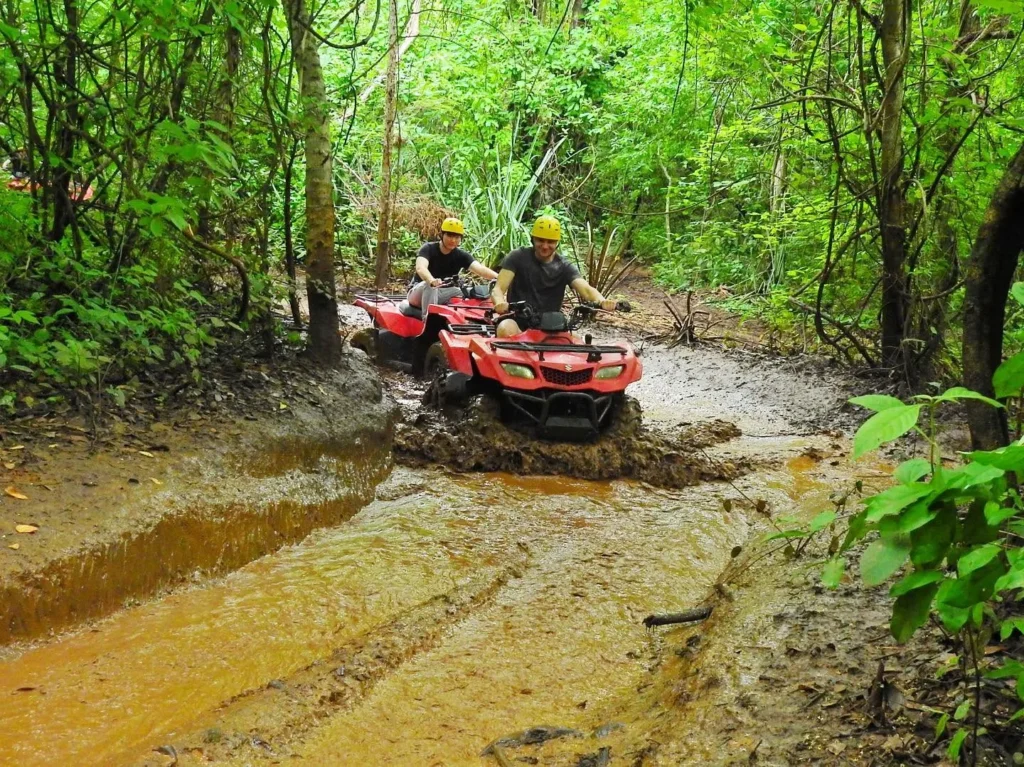 Adults crossing a muddy stream on ATVs in the rainy season at Congo Trail, Guanacaste, Costa Rica