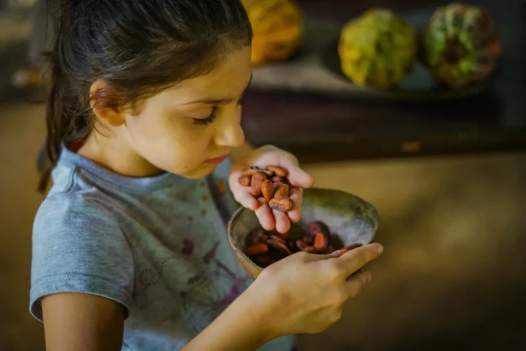 Child tasting roasted cacao beans on a private chocolate tour near Tenorio Volcano