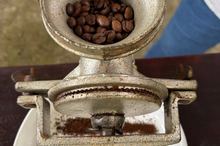 Hand-grinding roasted coffee beans on a traditional coffee tour in Guanacaste, Costa Rica