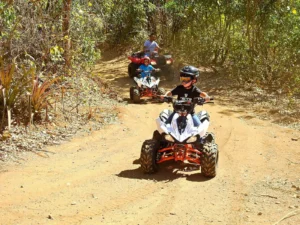 Children riding kid-sized ATVs on a dry-season forest trail with a guide at Congo Trail, Sardinal, Guanacaste, Costa Rica