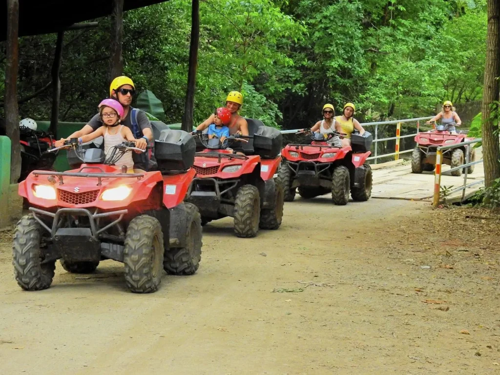 Families riding ATVs together crossing a bridge on a group tour at Congo Trail, Sardinal, Guanacaste