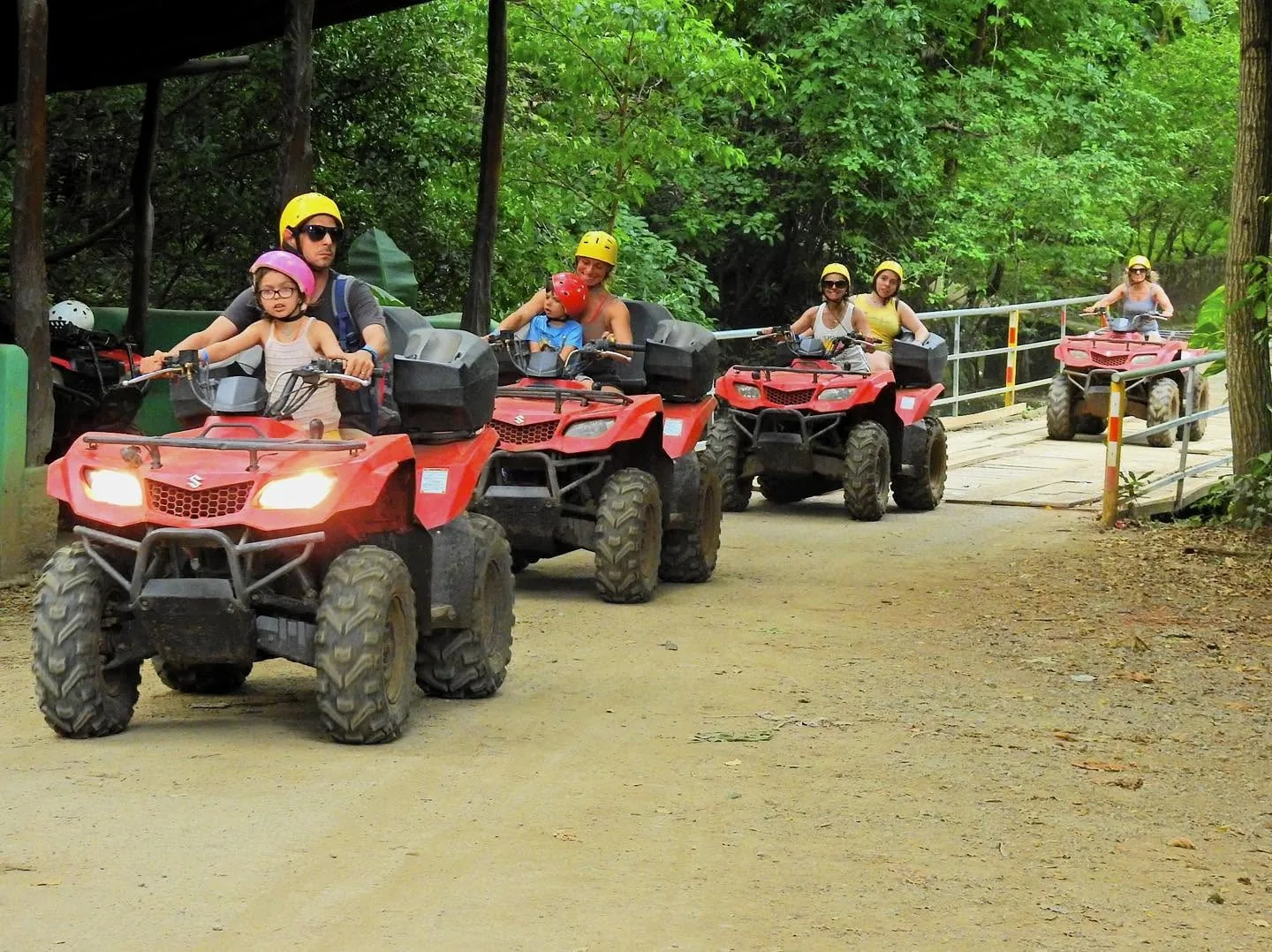 Families riding ATVs together crossing a bridge on a group tour at Congo Trail, Sardinal, Guanacaste