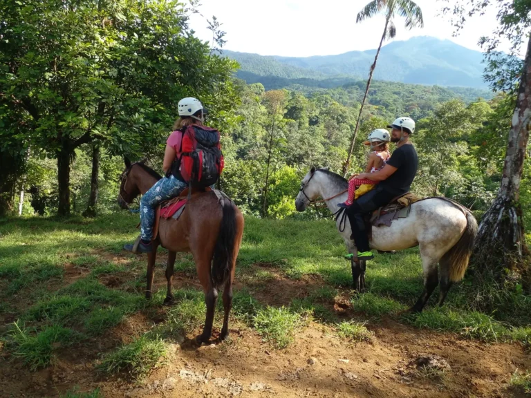 Family riding horses together on a Río Celeste horseback tour in the Tenorio rainforest, Costa Rica
