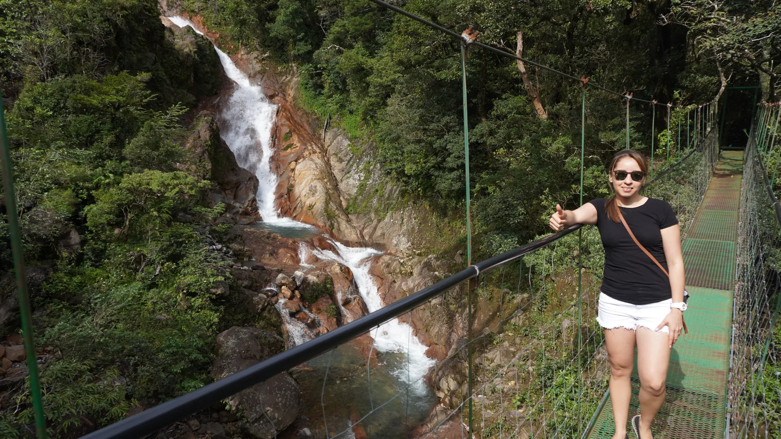 Couple on a suspension bridge beside a waterfall on a hanging bridges waterfall tour in Guanacaste