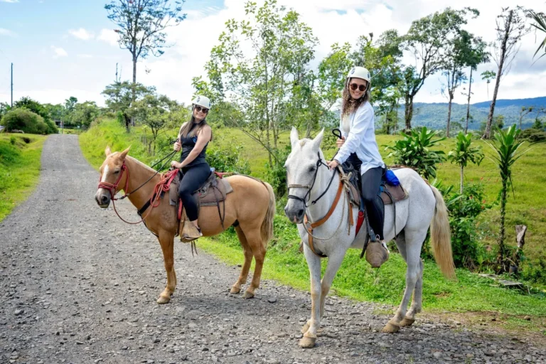 Two riders smiling on horseback on a horseback tour in the Tenorio rainforest, Costa Rica