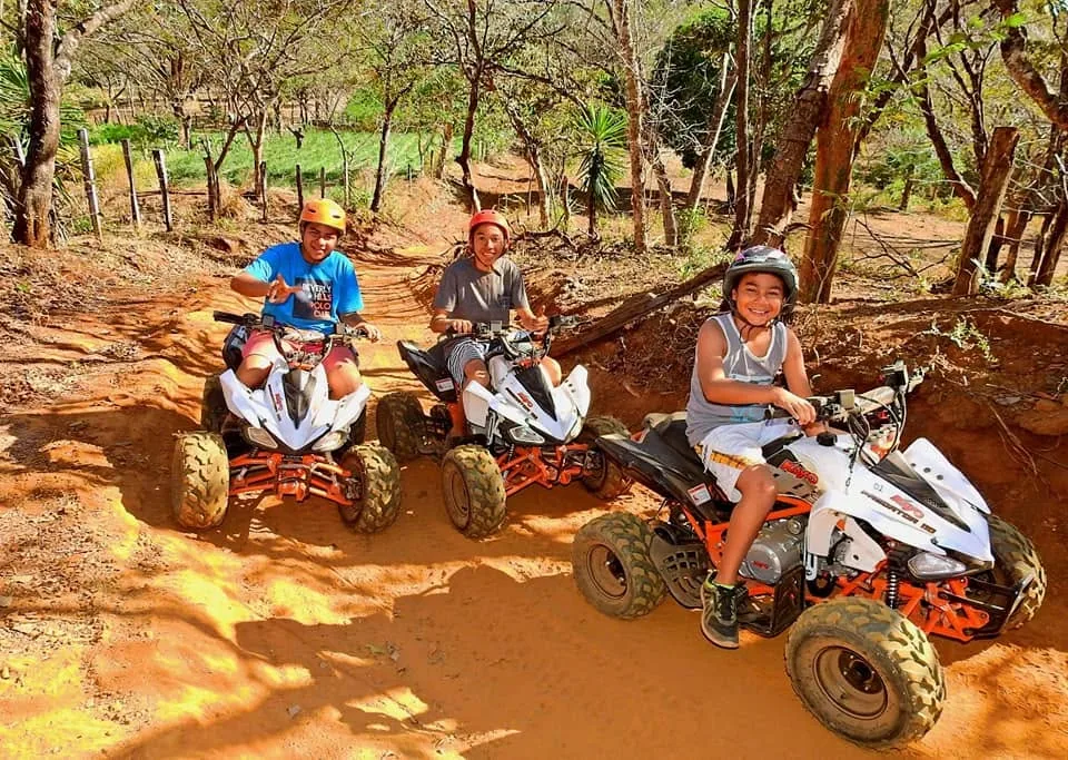 Three children smiling on kid-sized ATVs on a family ride at Congo Trail, Guanacaste, Costa Rica