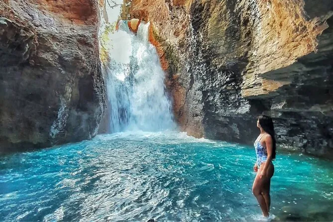 Swimmer admiring the La Leona waterfall and blue pool on a Guanacaste tour
