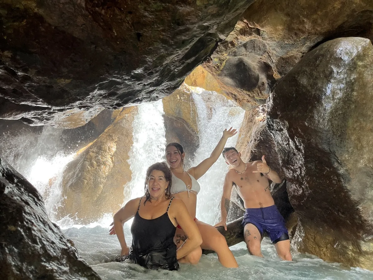 Travelers under the falls inside the La Leona canyon, Guanacaste tour, Costa Rica
