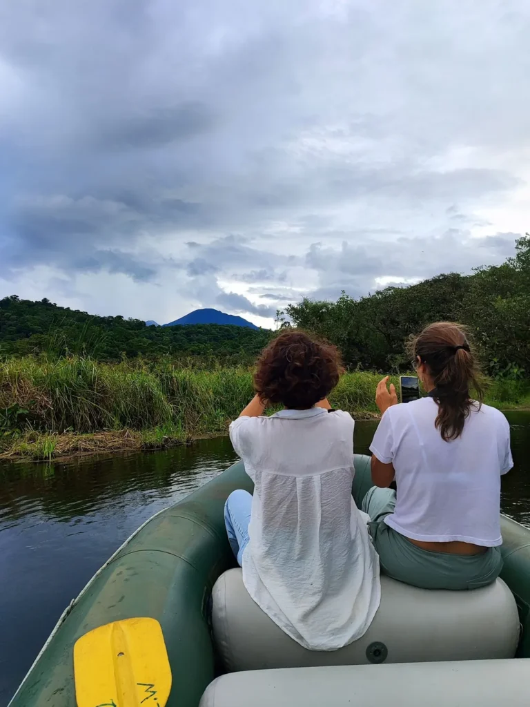 Visitors on a raft with Tenorio Volcano in the distance on a rainforest lagoon float tour, Costa Rica