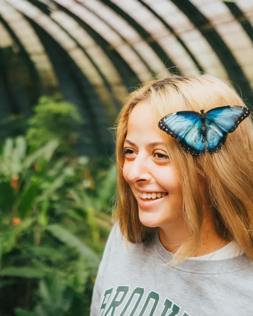 Smiling guest with a blue morpho butterfly in the Monteverde butterfly garden