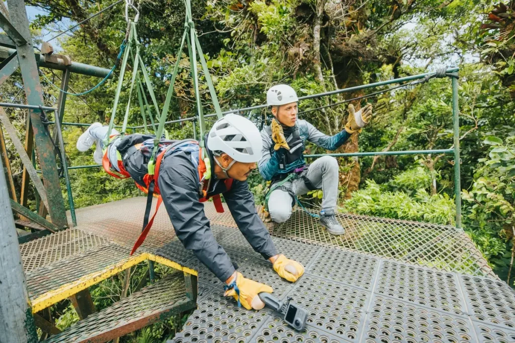 Guides preparing a visitor to launch from a zipline platform in the Monteverde cloud forest