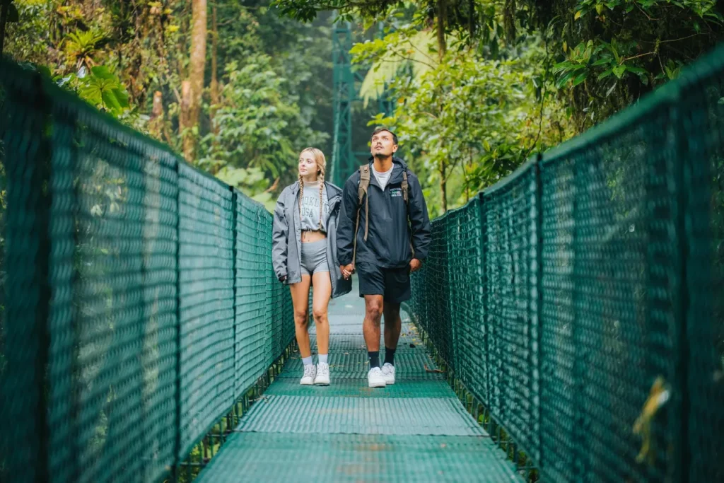 Guests crossing a hanging bridge on a misty Monteverde cloud forest tour