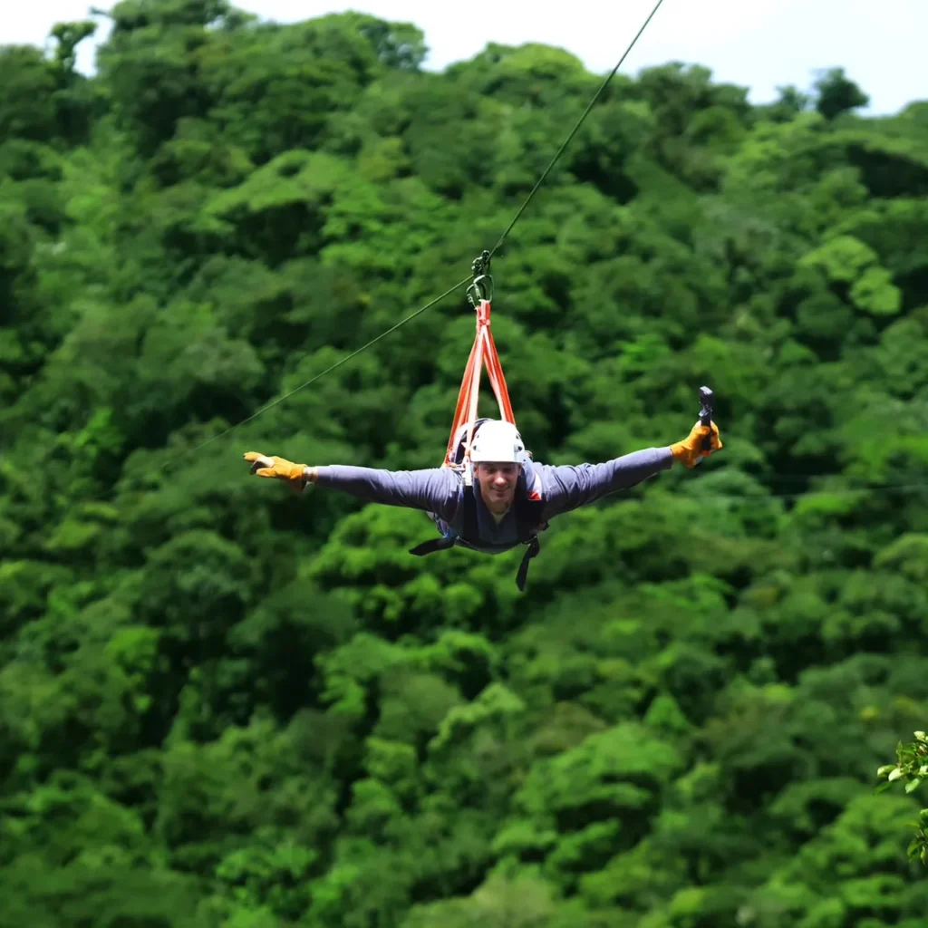 Adventurer gliding arms-out on a zipline above the Monteverde cloud forest