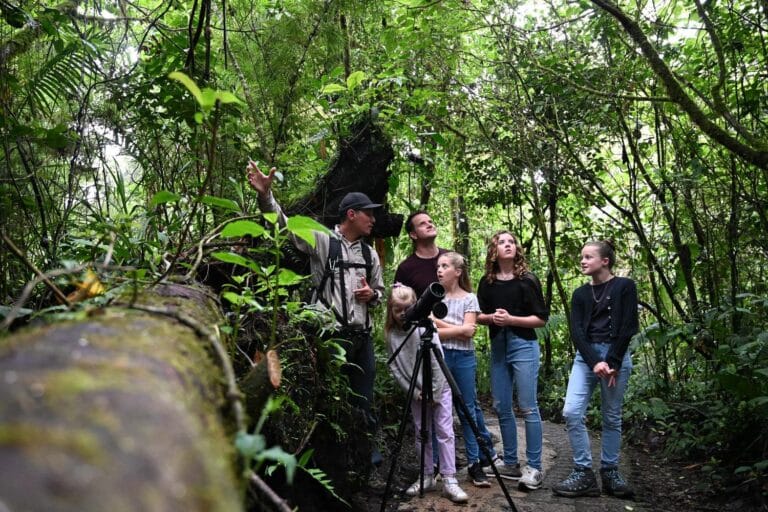 Naturalist guide showing a family wildlife through a spotting scope in the Tenorio rainforest, Costa Rica