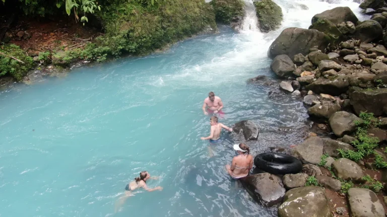 Family swimming in the milky-blue Río Celeste on a private swimming tour
