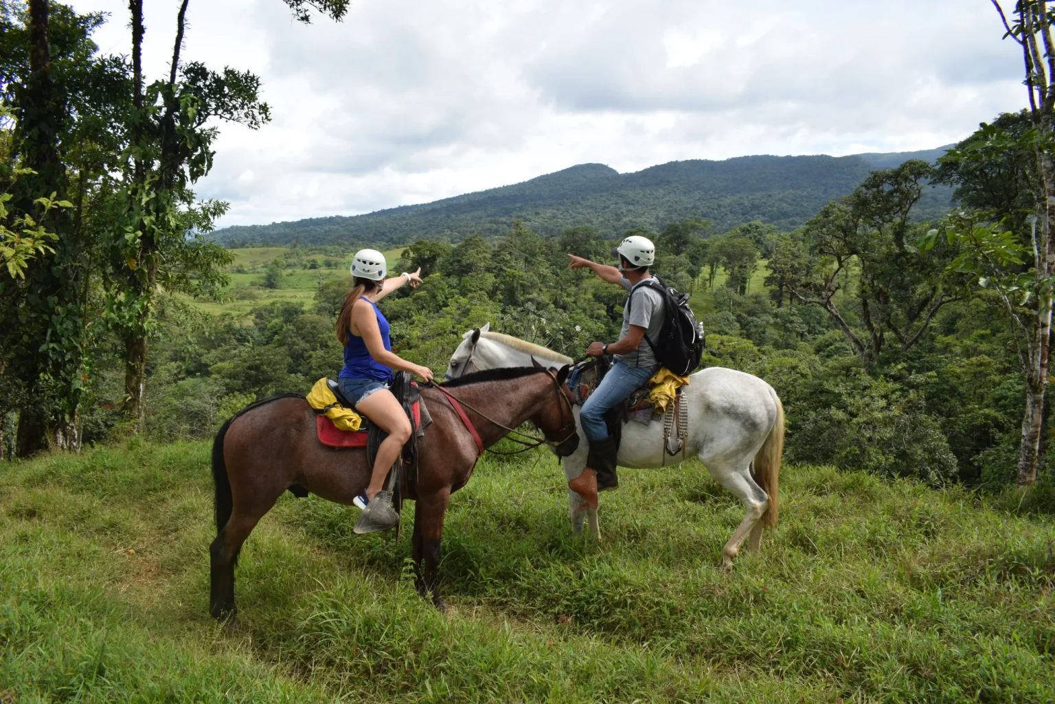 Couple on horseback taking in the rainforest valley on a Río Celeste horseback riding tour in the Tenorio rainforest, Costa Rica