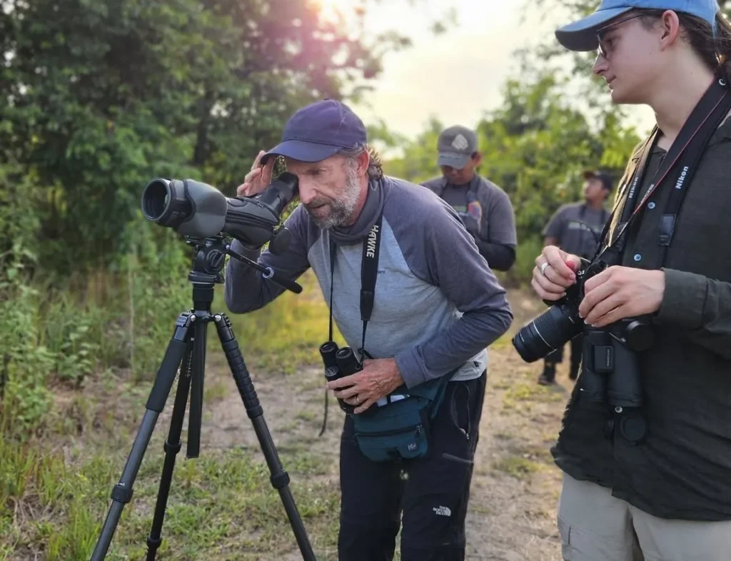 Naturalist guide with a spotting scope helping a photographer on a wildlife photography tour, Costa Rica