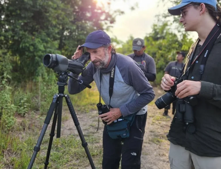 Naturalist guide with a spotting scope helping a photographer on a wildlife photography tour, Costa Rica