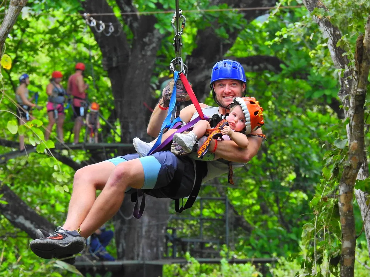 Father zip lining with a baby on a family-friendly canopy tour in Guanacaste, Costa Rica