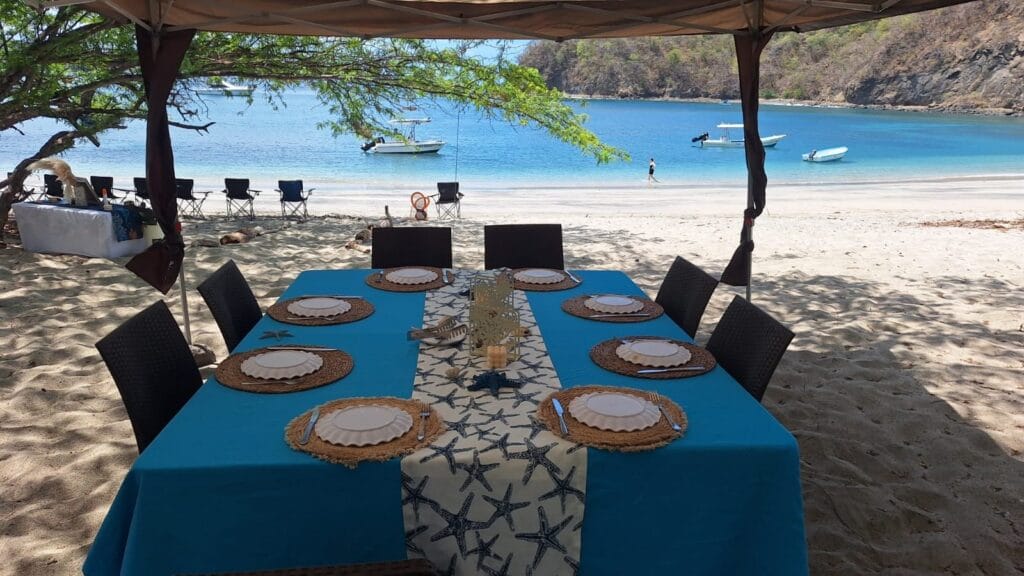 Table set under shade tents on a quiet beach for a private boat day barbecue in the Gulf of Papagayo, Guanacaste, Costa Rica