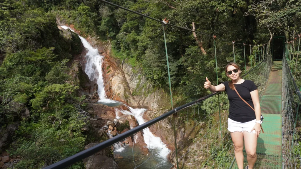 Karol Murillo Portilla, co-founder of Guanadreams CR private tours, on a hanging bridge over a waterfall in Costa Rica