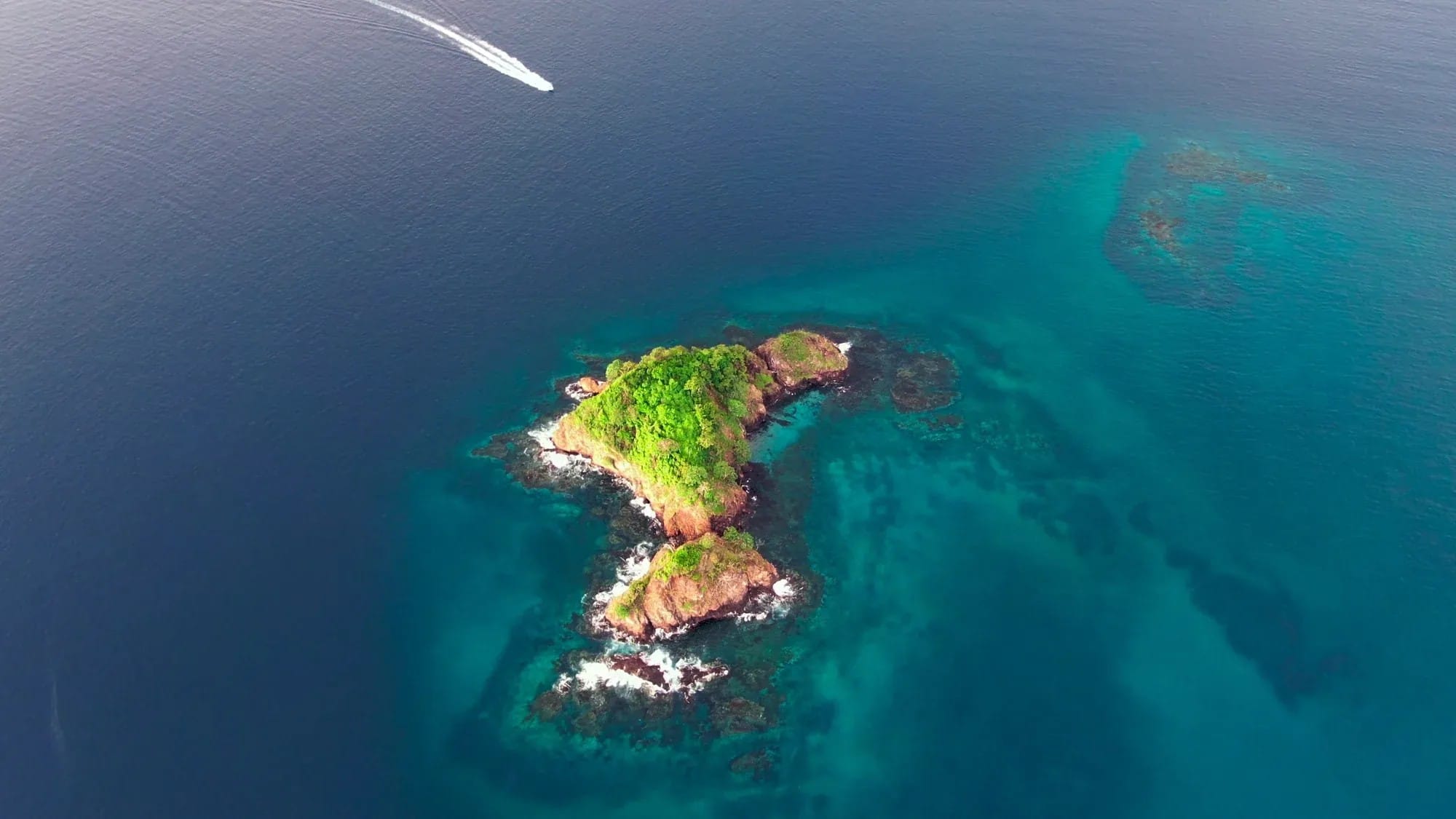 Aerial view of the turquoise Gulf of Papagayo with a private boat on a Guanacaste boat-day charter, Costa Rica