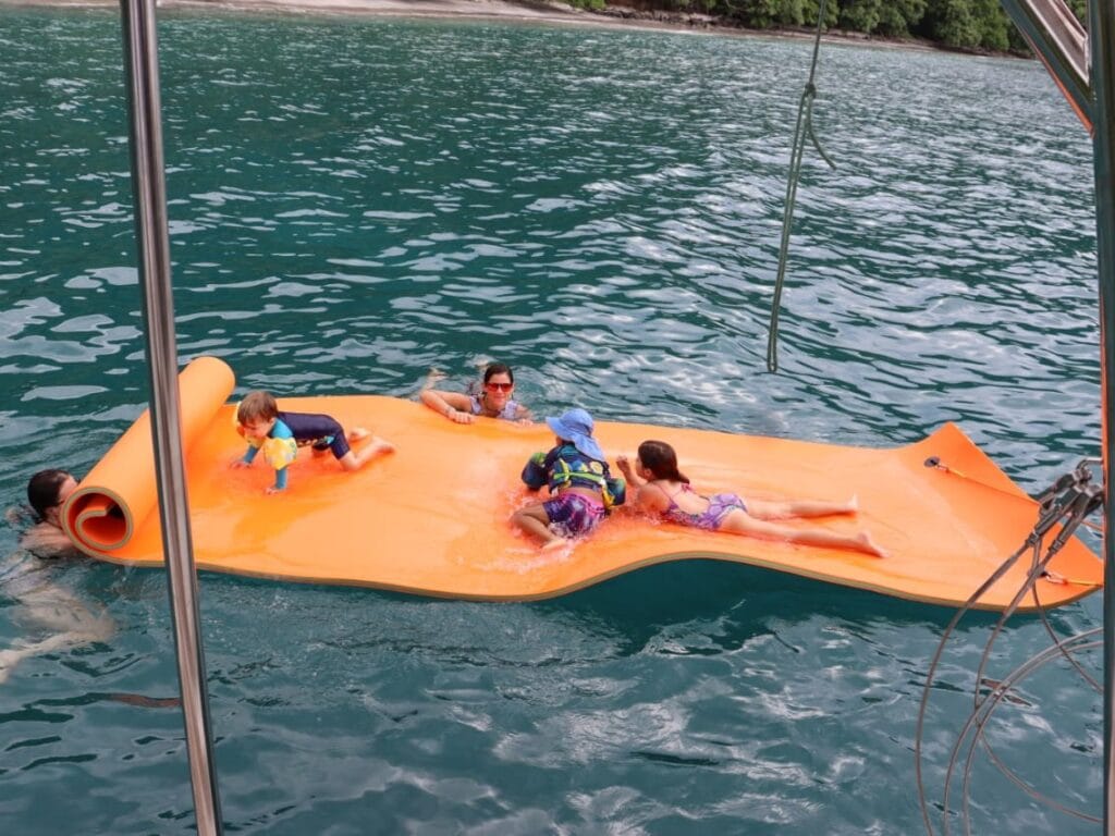Children swimming beside a private catamaran in the Gulf of Papagayo, Guanacaste, Costa Rica