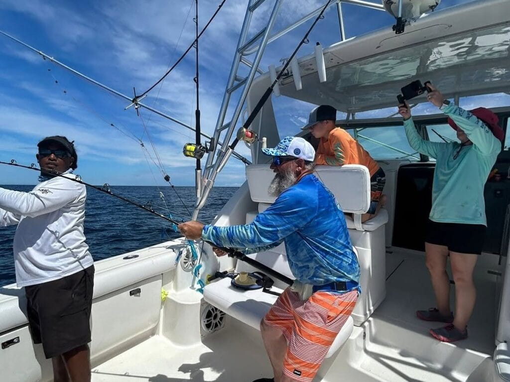 Angler fighting a fish from the deck while the mate assists, on a private charter in the Gulf of Papagayo, Costa Rica