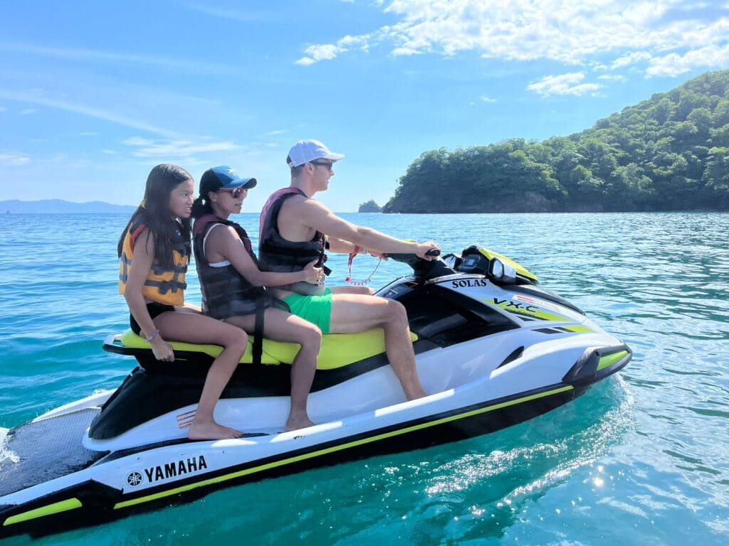 Three guests riding a wave runner together on calm water, Gulf of Papagayo, Guanacaste, Costa Rica