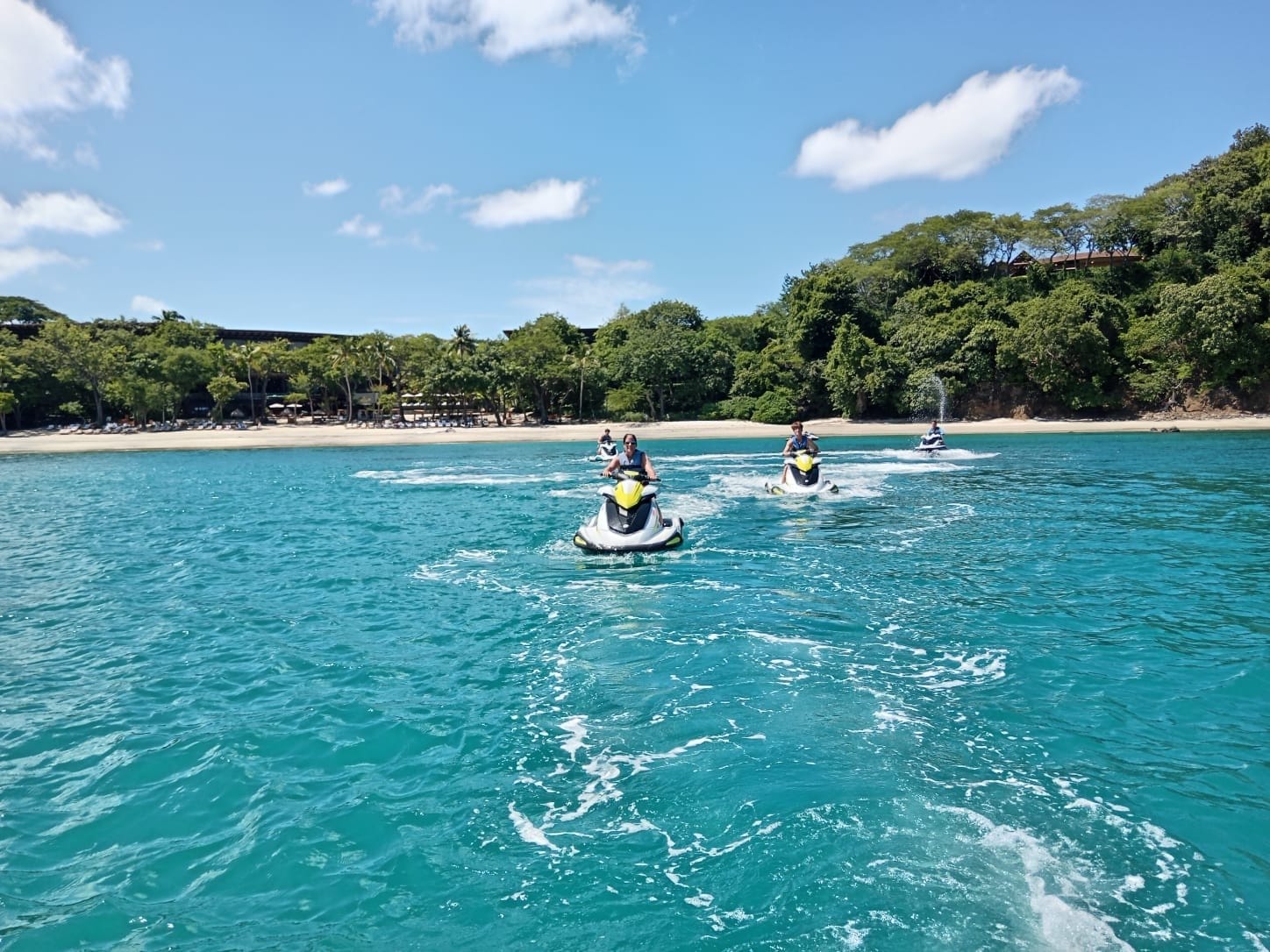Four wave runners riding across turquoise water past a white-sand beach, Gulf of Papagayo, Guanacaste, Costa Rica