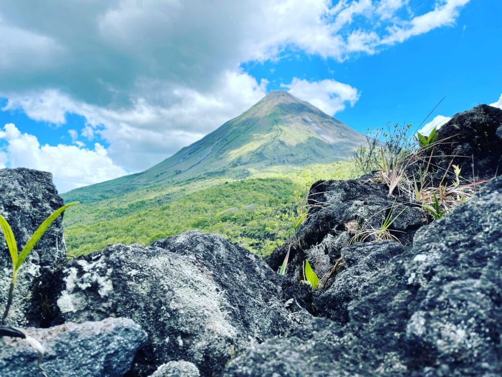 Arenal Volcano seen from the hardened 1968 lava flow, with pioneer plants growing between the rocks