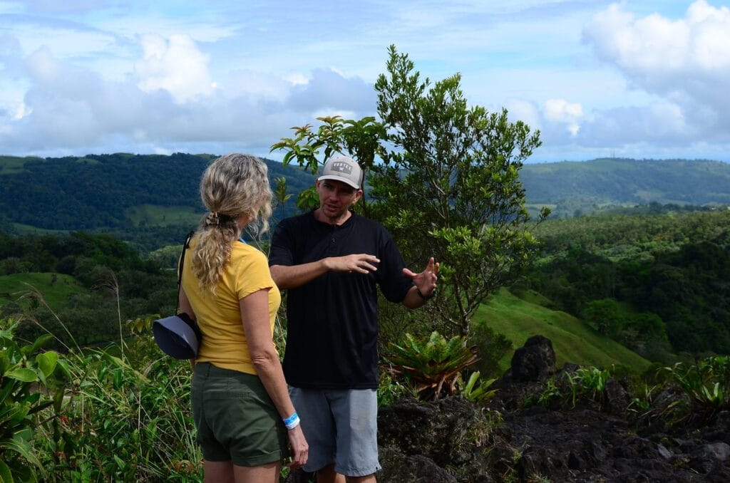 Guanadreams naturalist guide explaining the volcanic landscape to a visitor at an Arenal viewpoint