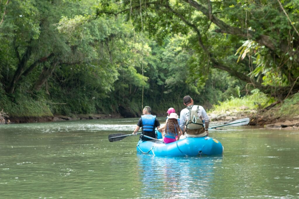 The guide paddling the raft down the Peñas Blancas while guests sit and watch, La Fortuna, Costa Rica