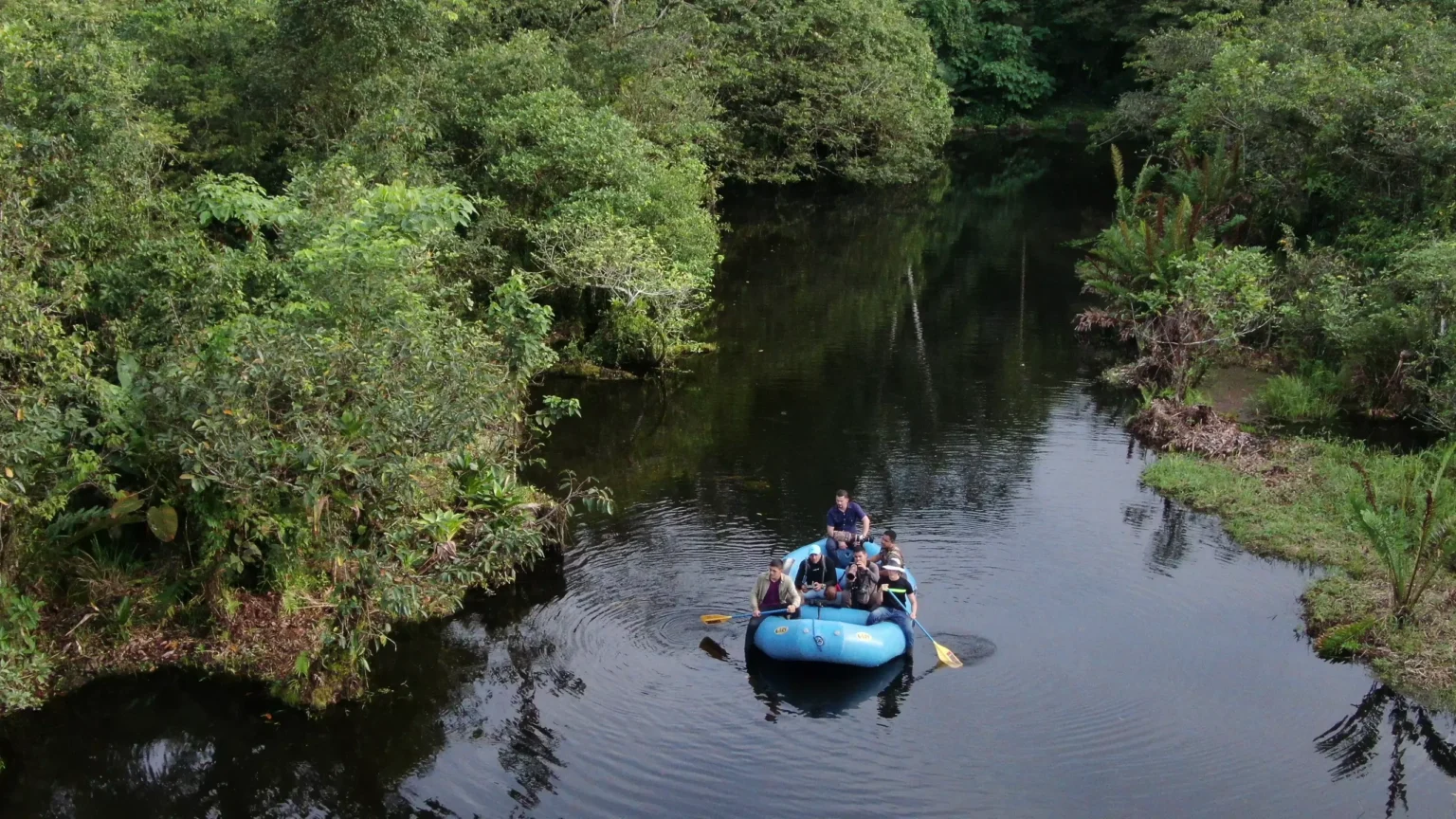 Guests on a raft drifting across a still rainforest lagoon in a private reserve in the Tenorio rainforest, Costa Rica