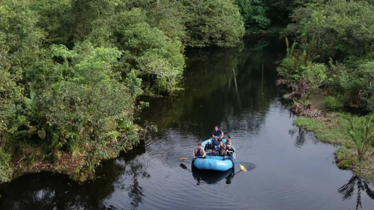 Guests on a raft drifting across a still rainforest lagoon in a private reserve in the Tenorio rainforest, Costa Rica